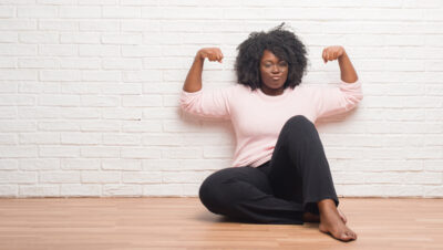 Young African American woman sits and flexes arms after conquering urge incontinence | CU Urogynecology | Denver, CO